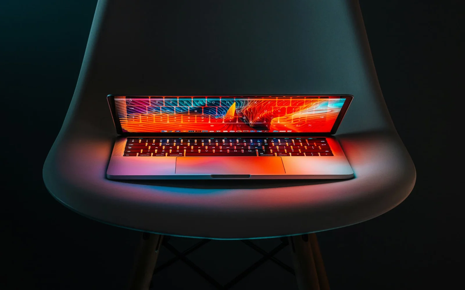 Notebook aberto sobre uma cadeira, com teclado iluminado