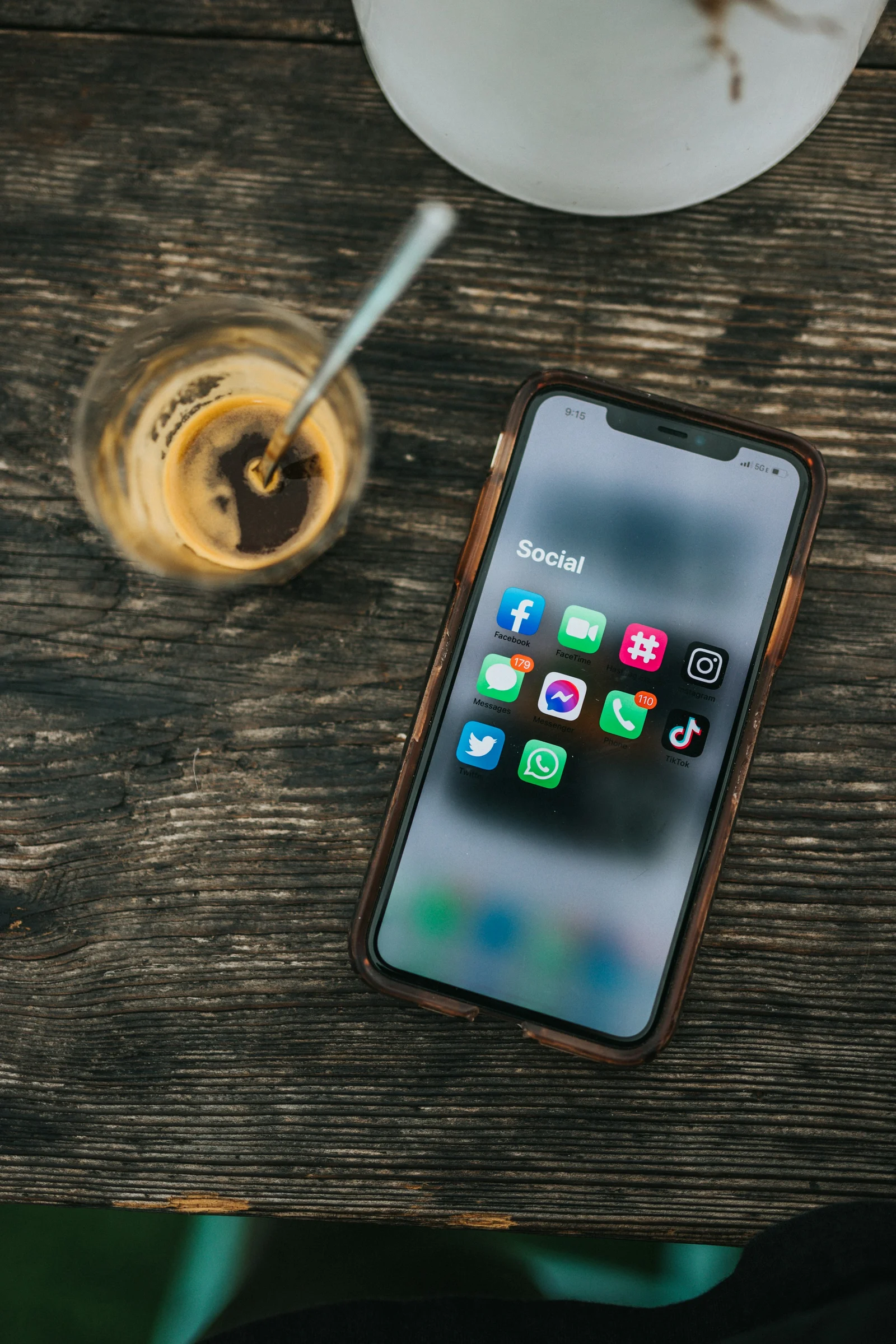 Smartphone com aplicativos de redes sociais ao lado de um copo de café