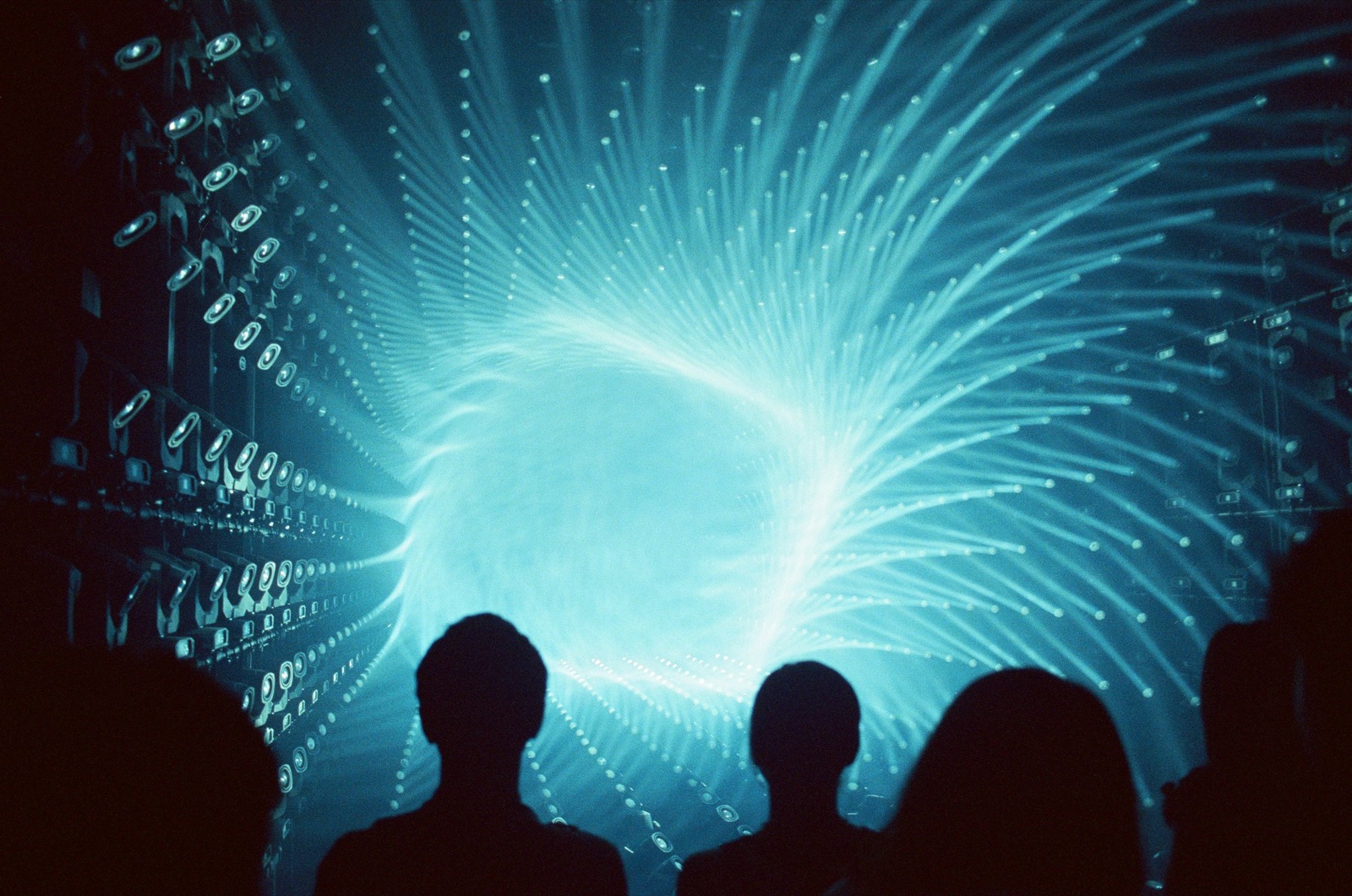 Silhuetas de pessoas diante de um túnel de feixes de luz azul