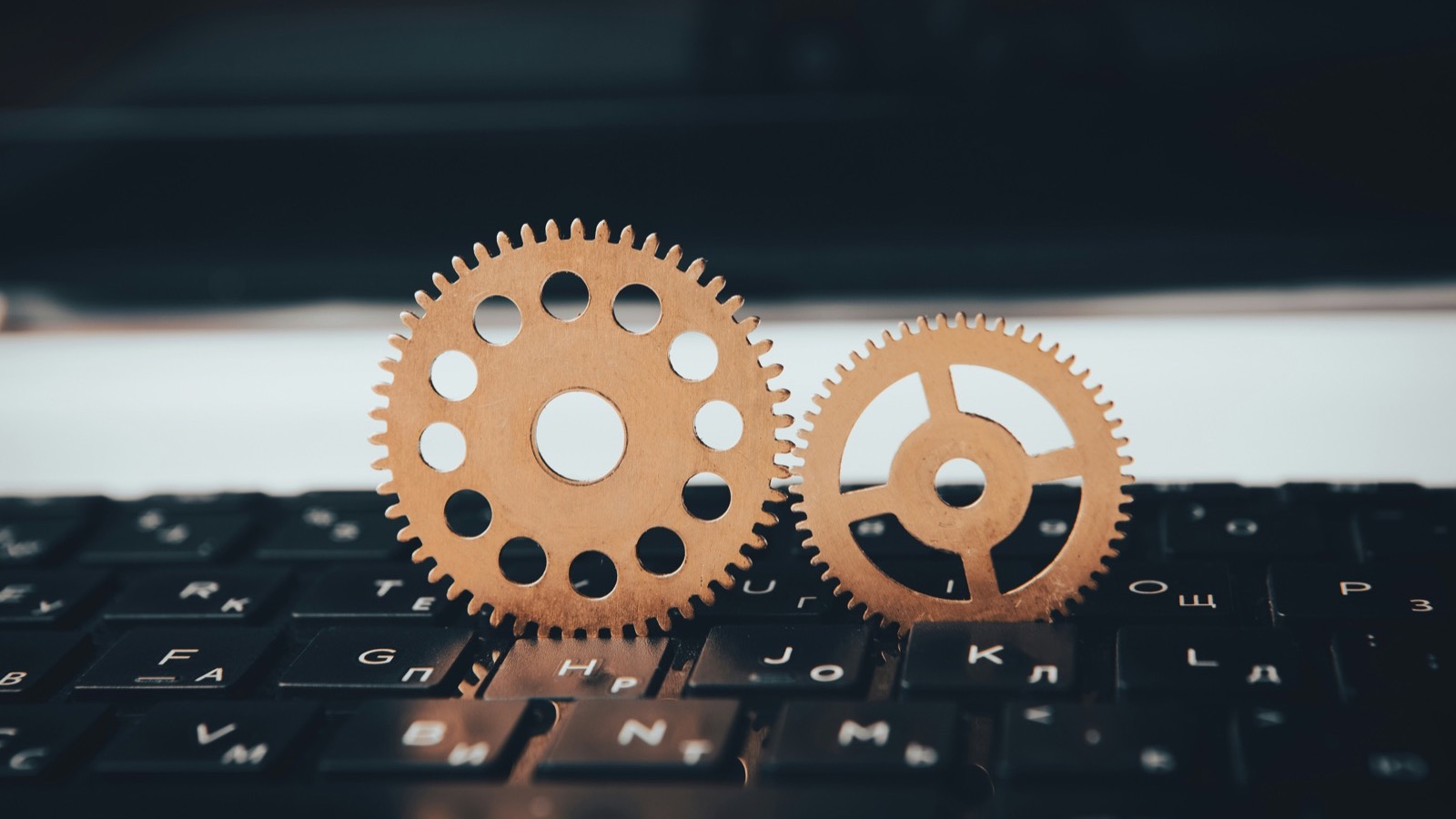 Duas engrenagens de madeira apoiadas sobre um teclado de computador preto